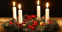 Four lit advent candles with a wreath